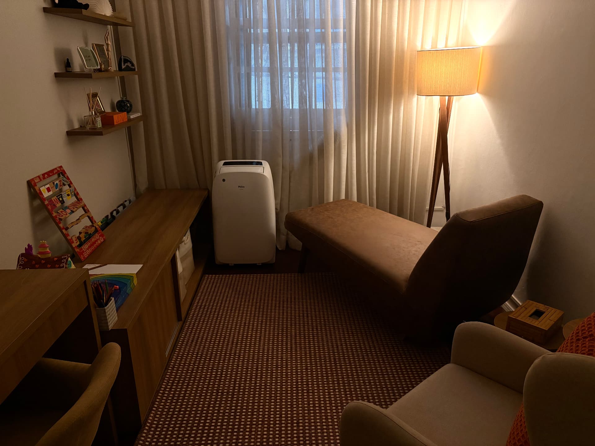 Consultório com divã, poltronas e luminária acesa